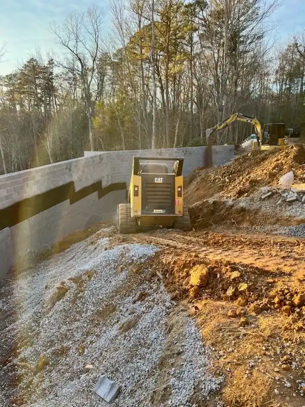 Excavator working beside a masonry retaining wall